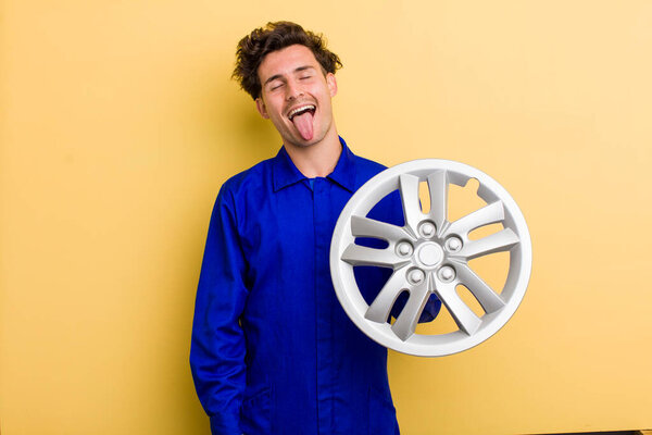 Молодой красивый подросток с веселым и бунтарским отношением, шутит и высовывает язык. концепция автомеханика