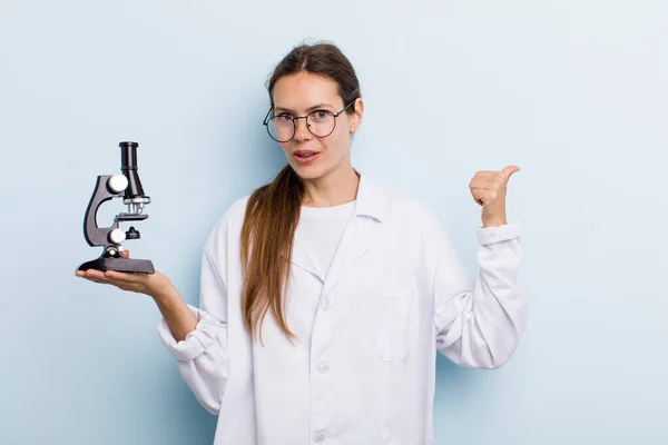 Νεαρή Ενήλικη Γυναίκα Που Δείχνει Έκπληκτη Από Δυσπιστία Επιστήμονας Μικροσκόπιο — Φωτογραφία Αρχείου