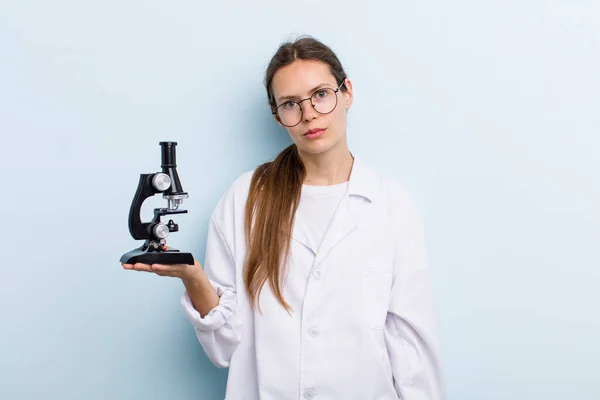 young adult woman feeling sad and whiney with an unhappy look and crying. scientist with a microscope