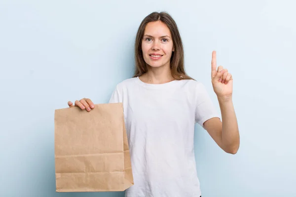 Young Adult Woman Smiling Looking Friendly Showing Number One Delivery – stockfoto