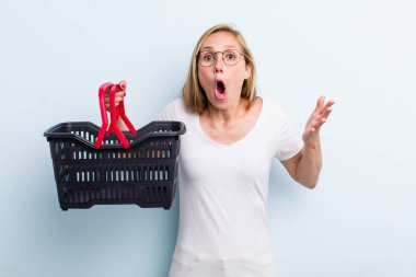 Sarışın, genç, yetişkin bir kadın inanılmaz bir sürprizle şaşkına döndü ve hayrete düştü. Alışveriş sepeti