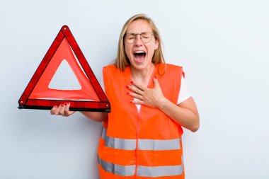 Sarışın, genç, yetişkin bir kadın komik bir şakaya yüksek sesle gülüyor. araba acil durumu