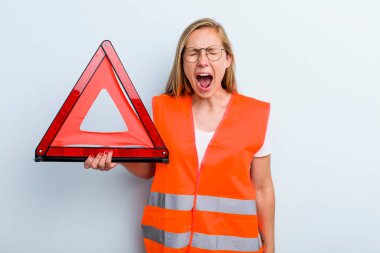 Sarışın, genç, yetişkin bir kadın agresif bir şekilde bağırıyor, çok kızgın görünüyor. araba acil durumu