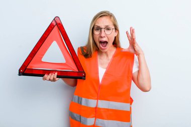 Sarışın, genç, yetişkin bir kadın ellerini havaya kaldırarak çığlık atıyor. araba acil durumu