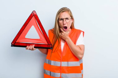 Sarışın, genç, yetişkin bir kadın. Ağzı ve gözleri açık ve elleri çenesinde. araba acil durumu