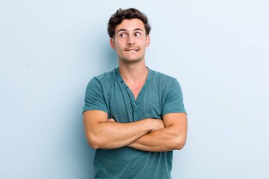 Genç yakışıklı adam şüphe ediyor ya da düşünüyor, dudağını ısırıyor ve kendini güvensiz ve gergin hissediyor, kenarda yer arıyor.