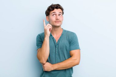 Genç yakışıklı adam mutlu bir şekilde gülümsüyor ve yan bakıyor, merak ediyor, düşünüyor ya da bir fikri var.