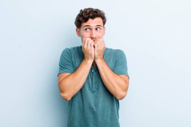 Genç yakışıklı adam endişeli, endişeli, stresli ve korkmuş görünüyor, tırnaklarını yiyor ve yanal fotokopi alanı arıyor.