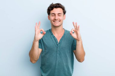 Genç yakışıklı adam konsantre olmuş ve meditasyon yapıyor, kendini tatmin olmuş ve rahatlamış hissediyor, düşünüyor ya da bir seçim yapıyor.