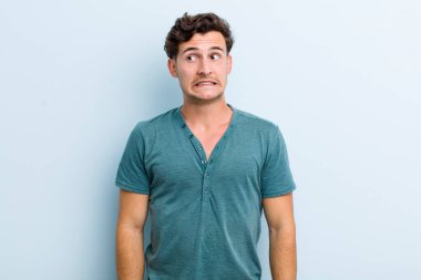 Genç, yakışıklı, endişeli, endişeli, korkmuş, panikleyen ve dişlerini sıkan bir adam.