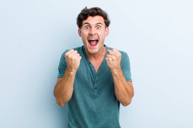 Genç yakışıklı adam sinirli, sinirli, sinirli bakışlar ve sıkı yumruklar ile agresif bir şekilde bağırıyor.