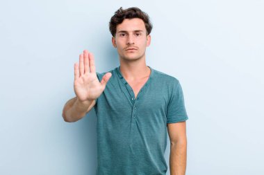 Genç ve yakışıklı adam ciddi, sert, hoşnutsuz ve kızgın görünüyor.