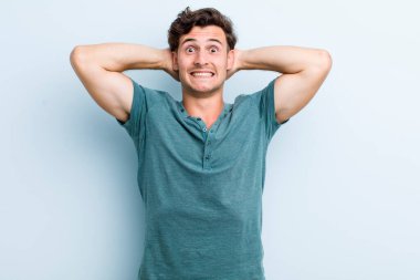 Genç ve yakışıklı bir adam stresli, endişeli, endişeli ya da korkmuş, elleri başının üstünde, hata yaptığında panikliyor.