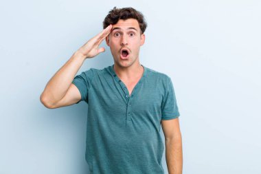 Genç yakışıklı adam mutlu, şaşkın ve şaşırmış görünüyor, gülümsüyor ve inanılmaz ve inanılmaz iyi haberleri fark ediyor.