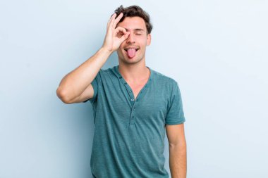 Genç yakışıklı adam mutlu bir şekilde gülümsüyor, şaka yapıyor ve gözetleme deliğinden bakıyor, sırları gözetliyor.