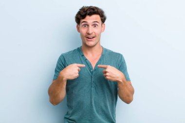 Genç yakışıklı adam mutlu, şaşkın ve gururlu, heyecanlı, şaşkın bakışlarıyla kendini işaret ediyor.