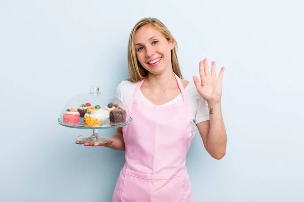 Blonde Young Adult Woman Smiling Happily Waving Hand Welcoming Greeting — Stockfoto