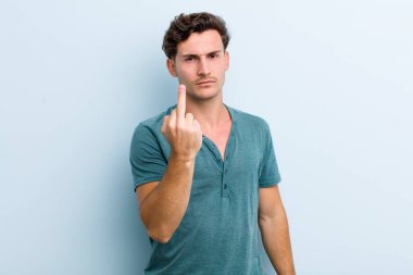 Genç, yakışıklı bir adam kızgın, sinirli, asi ve agresif orta parmağını sallayarak karşılık veriyor.