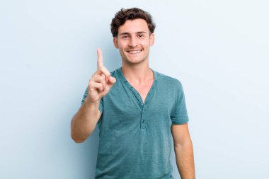 Genç yakışıklı adam gülümsüyor ve arkadaş canlısı görünüyor, bir numara ya da ilk eli önde, geriye doğru sayıyor.