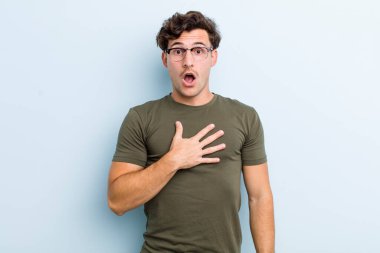 Genç yakışıklı adam şaşkın, şaşkın ve şaşırmış hissediyor, elleri göğsünde ve ağzı açık, kim diyor, ben mi??