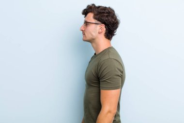 Profil görünümündeki genç yakışıklı adam ilerideki boşluğu kopyalamaya çalışıyor, düşünüyor, hayal ediyor ya da hayal kuruyor.