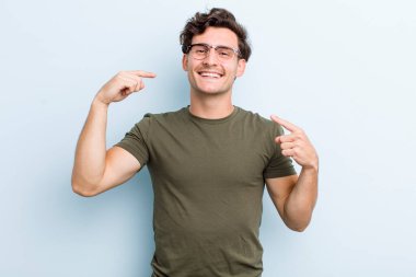 Genç yakışıklı adam, kendine güvenerek gülümsüyor. Geniş bir gülümseme, pozitif, rahat, tatmin olmuş bir tavır.