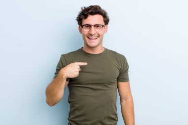 Genç yakışıklı adam mutlu, gururlu ve şaşırmış görünüyor, neşeli bir şekilde kendini gösteriyor, kendinden emin ve yüce hissediyor.