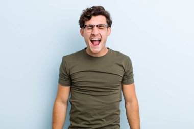 Genç yakışıklı adam agresif bir şekilde bağırıyor, çok kızgın, hayal kırıklığına uğramış, öfkeli ya da sinirli görünüyor, hayır