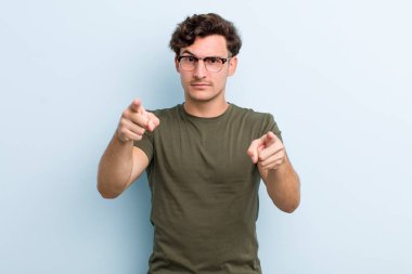 Genç ve yakışıklı bir adam kameraya hem parmaklarını hem de kızgın yüzünü göstererek sana görevini yapmanı söylüyor.