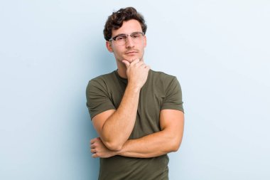 Genç yakışıklı adam ciddi görünüyor, kafası karışık, kararsız ve düşünceli, seçenekler ve seçimler arasında şüpheci.