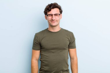 Genç yakışıklı adam mutlu ve arkadaş canlısı görünüyor, gülümsüyor ve sana olumlu bir tavırla göz kırpıyor.