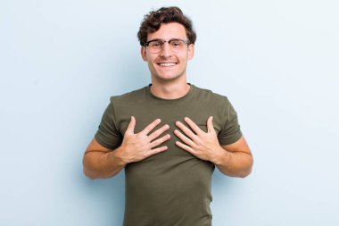 Genç yakışıklı adam mutlu görünüyor, şaşırmış, gururlu ve heyecanlı, kendini gösteriyor.