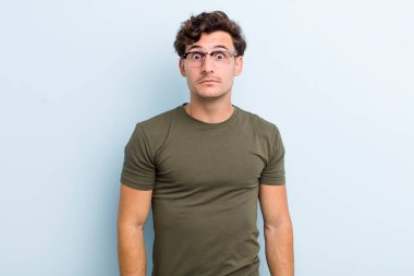 Aptal, çılgın, şaşkın bir ifadeyle genç yakışıklı adam, yanakları şişmiş, doldurulmuş, şişman ve yemekle dolu.