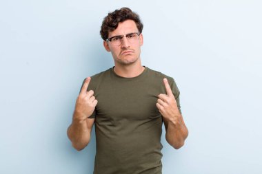 Kötü tavırlı genç yakışıklı adam gururlu ve agresif görünüyor, yukarıyı işaret ediyor ya da elleriyle alay işareti yapıyor.