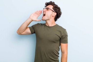 Genç yakışıklı adam öfkeyle bağırıyor kenardaki boşluğu kopyalasın diye, eli ağzının yanında.