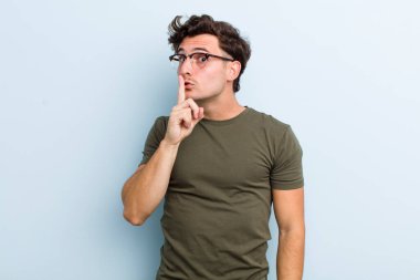 Genç yakışıklı adam sessizlik ve sessizlik istiyor, parmağıyla ağzının önünde işaret ediyor, 