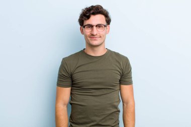 Genç yakışıklı adam pozitif ve kendinden emin gülümsüyor. Tatmin olmuş, arkadaş canlısı ve mutlu görünüyor.