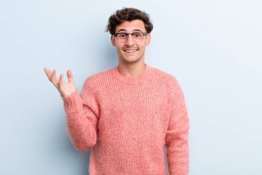 Genç yakışıklı adam kendini mutlu, şaşırmış ve neşeli hissediyor. Pozitif bir tavırla gülümsüyor. Bir çözüm ya da fikir buluyor.