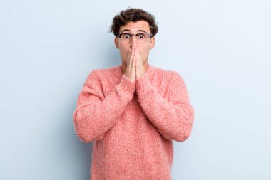 Genç yakışıklı adam endişeli, üzgün ve korkmuş, elleri ağızda, endişeli ve berbat görünüyor.