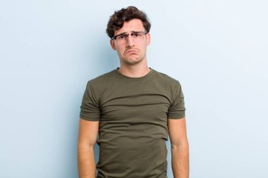 Genç yakışıklı adam üzgün ve mızmız, mutsuz bir bakışla, olumsuz ve hayal kırıklığına uğramış bir tavırla ağlıyor.