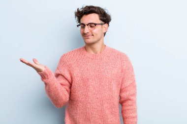 Genç yakışıklı adam kendini mutlu hissediyor ve gülümsüyor. Yanında duran bir nesneye ya da konsepte bakıyor.