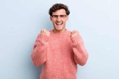 Genç yakışıklı adam zaferle bağırıyor, gülüyor, mutlu ve heyecanlı hissediyor başarıyı kutlarken.