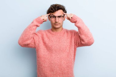 Ciddi ve konsantre görünümlü, beyin fırtınası yapan ve zorlu bir sorunu düşünen genç yakışıklı bir adam.