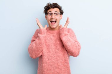 Genç ve yakışıklı bir adam beklenmedik bir sürpriz yüzünden şaşkın ve heyecanlı, güler yüzlü, şaşkın ve mutlu hissediyor.