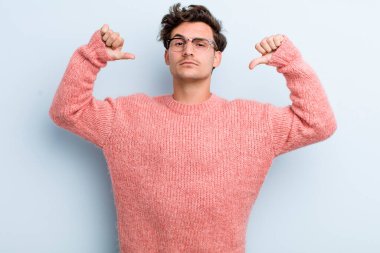 Genç yakışıklı adam gururlu, kibirli ve kendinden emin, tatmin olmuş ve başarılı görünüyor, kendini işaret ediyor.