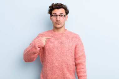 Kafası karışmış, kafası karışmış ve kendine güveni olmayan genç yakışıklı bir adam kendini göstererek kim olduğunu soruyor, ben mi??