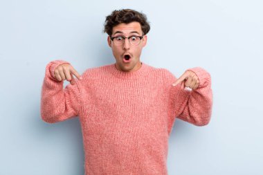 Genç yakışıklı adam şok olmuş, ağzı açık ve şaşkın, inançsızlık ve şaşkınlık içinde bakıyor ve onu işaret ediyor.