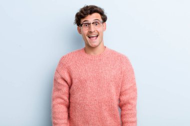 Genç yakışıklı adam mutlu ve hoş bir şekilde şaşırmış görünüyor. Büyülenmiş ve şok olmuş bir ifadeyle heyecanlanıyor.