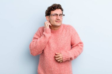 Genç ve yakışıklı bir adam stresli, hayal kırıklığına uğramış ve yorgun, endişeli ve sorunlu bir bakışla boynunu okşuyor.