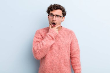 Ağzı ve gözleri açık, eli çenesinde genç ve yakışıklı bir adam. Hoş olmayan bir şok geçiriyor.